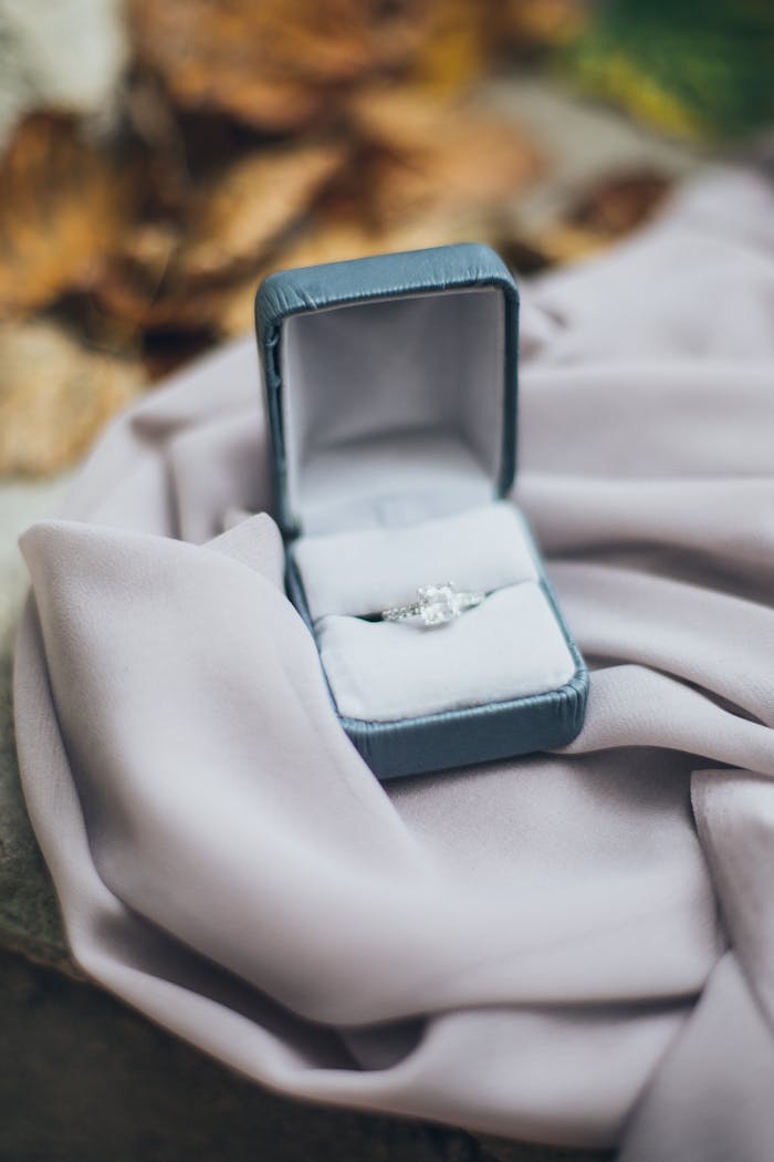 An elegant diamond ring in an open jewelry box resting on soft fabric, evoking love and commitment.